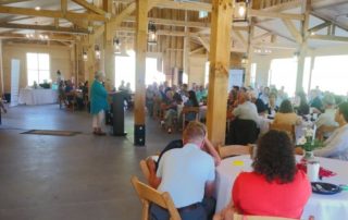 people eating at tables listening to a speaker